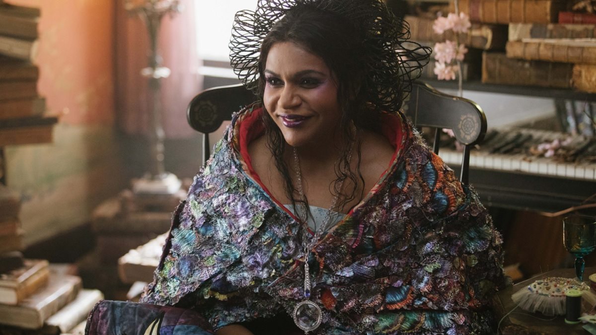 Mindy Kaling as Mrs Who surrounded by stacks of books in A Wrinkle In Time movie