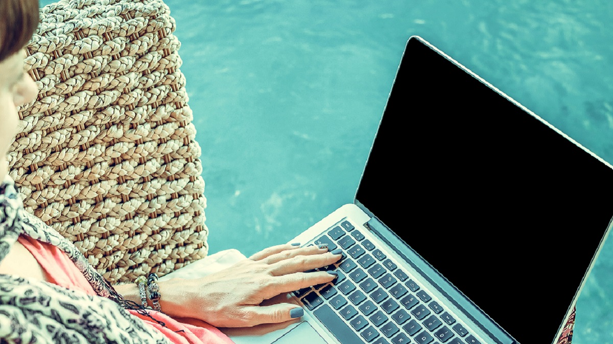 woman using laptop near swimming pool