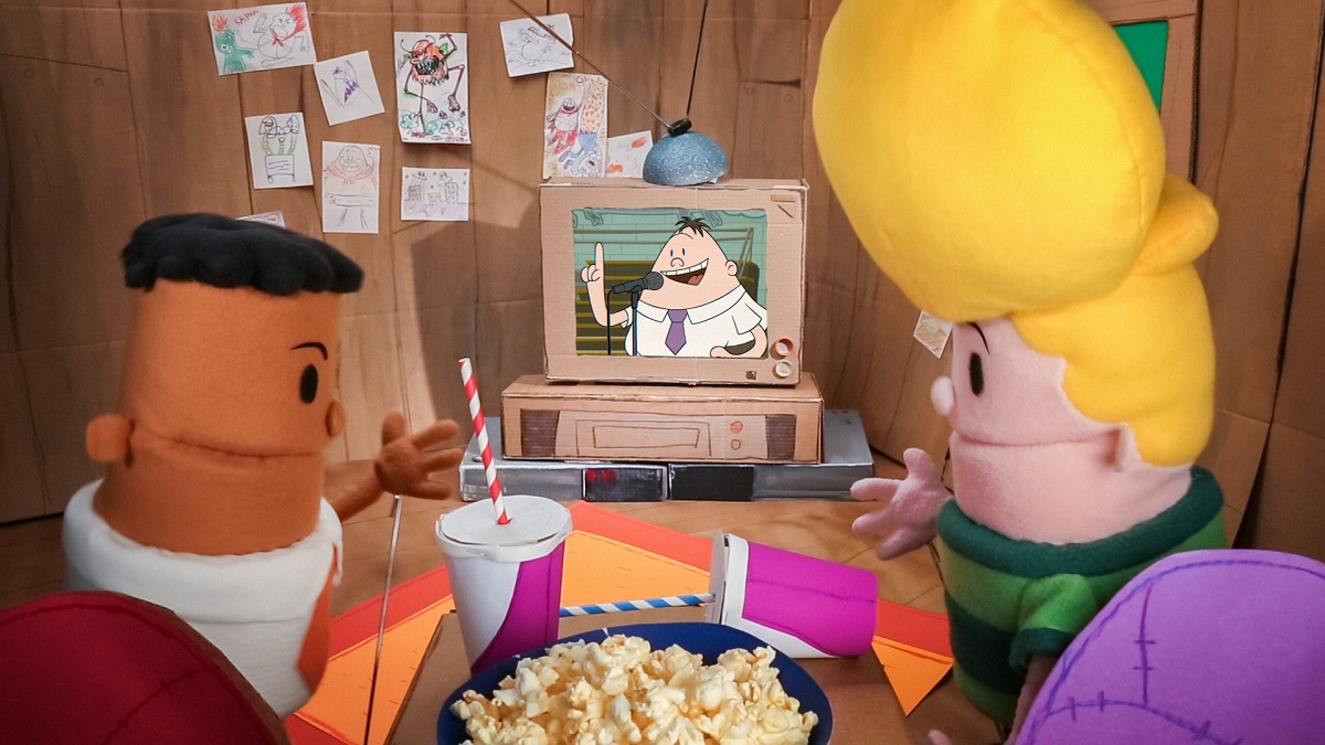 Puppet versions of George Beard and Harold Hutchins watch an animated Principal Krupp on TV in this still from 'The Epic Tales of Captain Underpants'