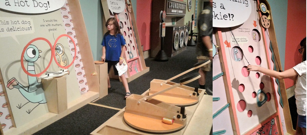 Two catapults facing movable hoops being cranked by 11yo, in front of Pigeon and Duckling picture; board with holes with a pulley device for lifting "cookies" to holes for the Pigeon or Duckling