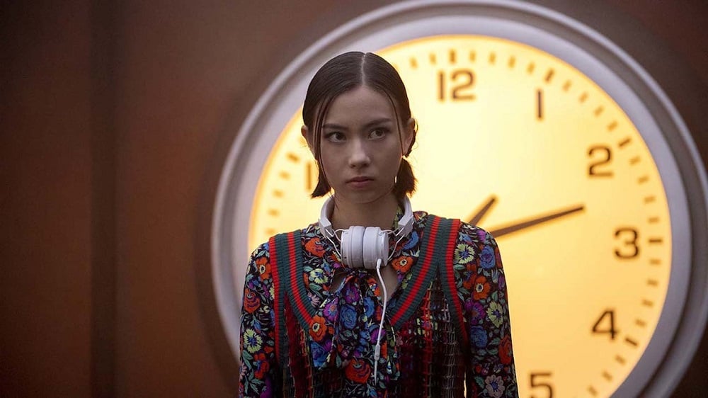 Lauren Tsai as Switch, looking incredulous in front of a big clock