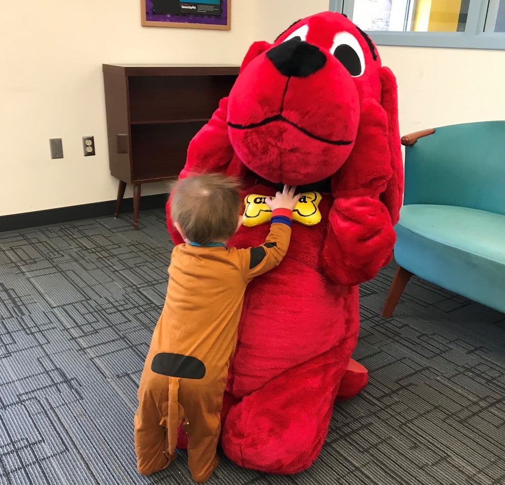 toddler dressed as Scooby-Doo dives at person dressed as Clifford, who is leaning away in exaggerated shock