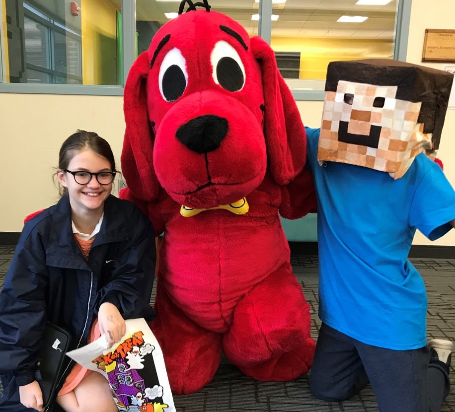 Person in Clifford costume poses with preteens dressed as Eleven from Stranger Things and Steve from Minecraft