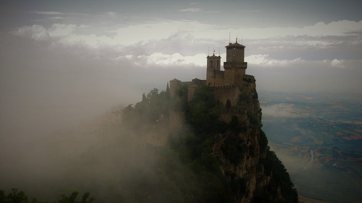 castle on a mountain surrounded by cloud