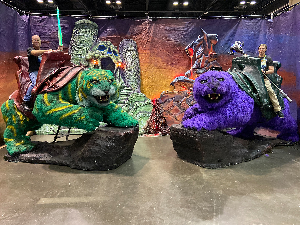 two people sitting on green Cringer from He-Man and Panthor from Skeletor